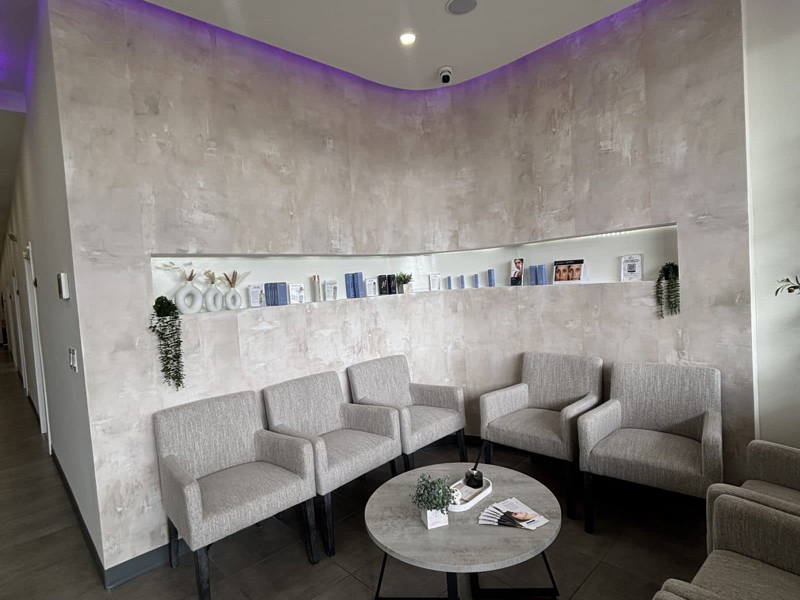 The waiting lounge at Rewind Bar, with armchairs beneath a lit shelf of skincare