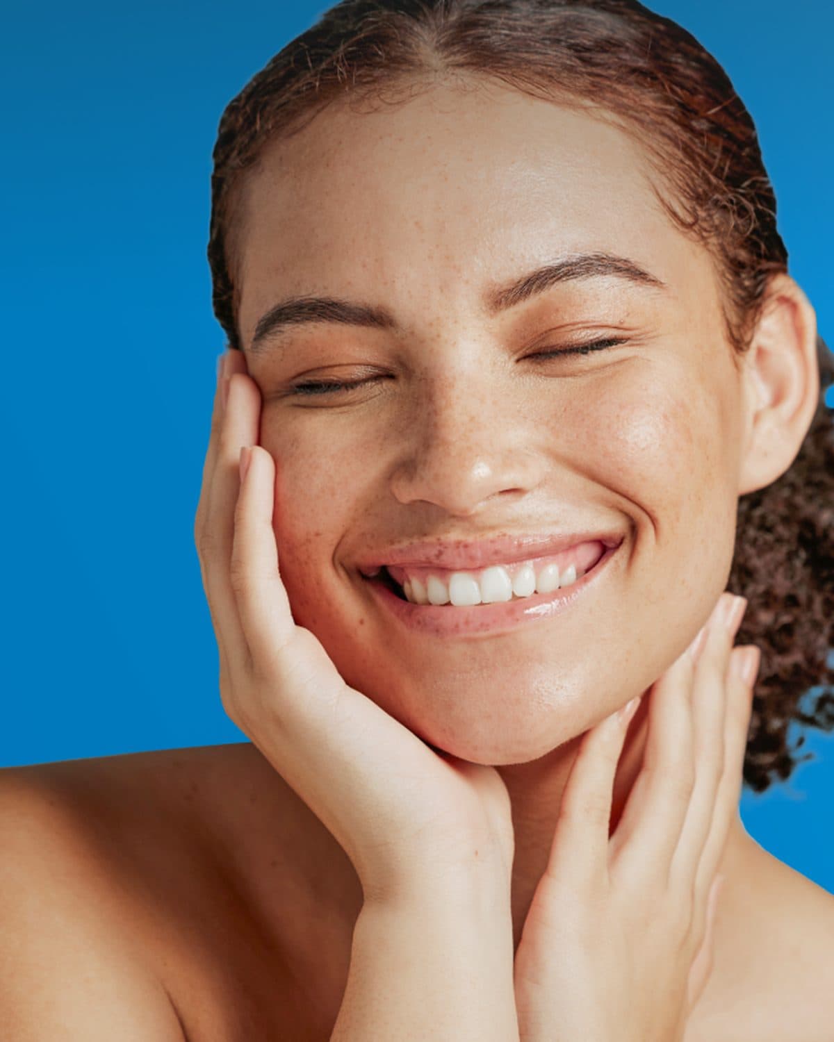 Smiling woman with fresh, hydrated skin holding her hands to her face