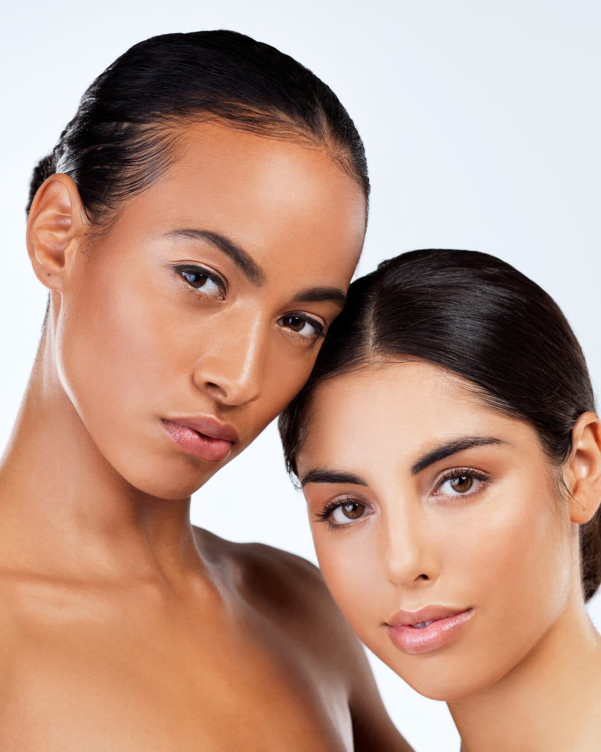 Two women with clear, even-toned skin, cheek to cheek